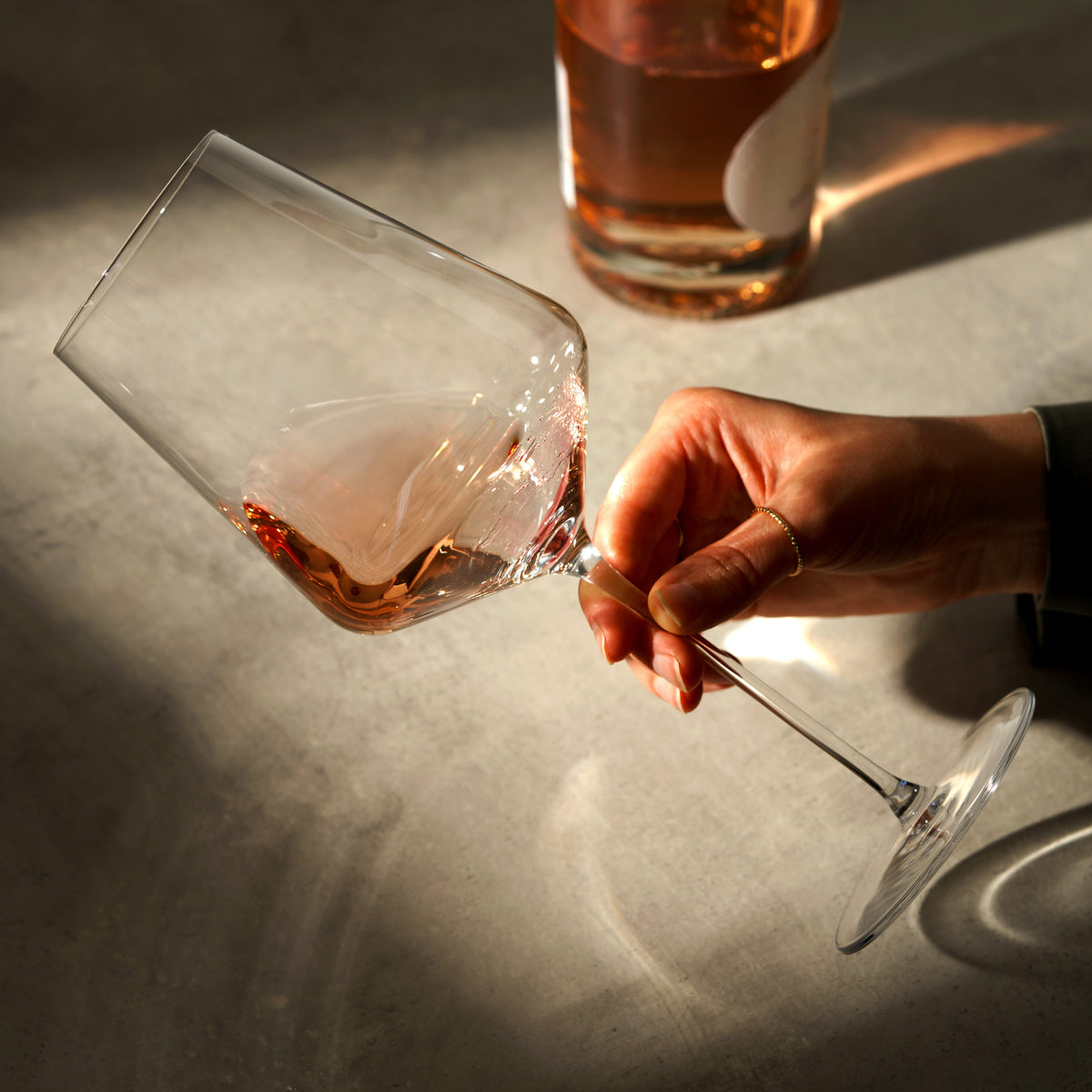 Liminal universal wine glass held by hand with rosé wine, foreground visible on Tampa Home & Garden Store