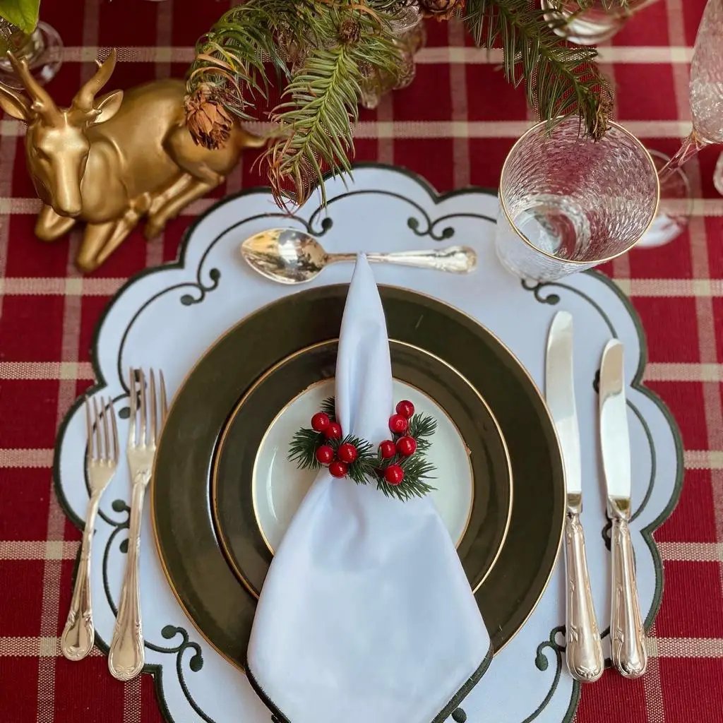 White cotton napkin with green trim, elegantly folded on a festive place setting by Talah Home on Tampa Home & Garden Store