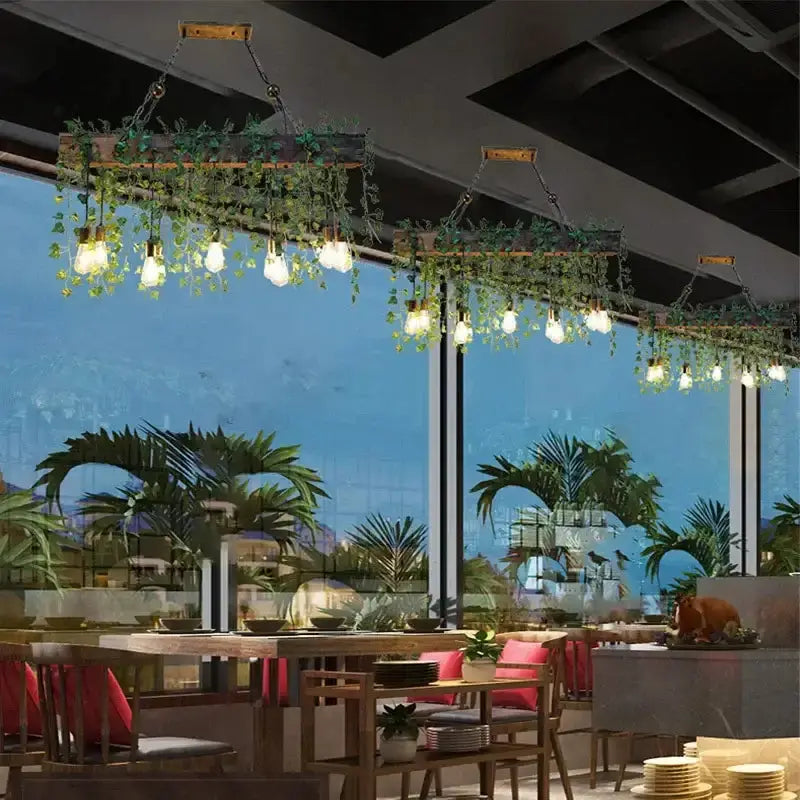 Three rustic wood hanging chandeliers with greenery and Edison bulbs over a dining table on Tampa Home & Garden Store