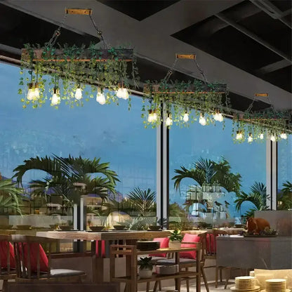 Three rustic wood hanging chandeliers with greenery and Edison bulbs over a dining table on Tampa Home & Garden Store