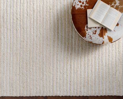 Debra Area Rug by Boutique Rugs, beige looped-pile rug; subtle stripes, brown cowhide ottoman on Tampa Home & Garden Store