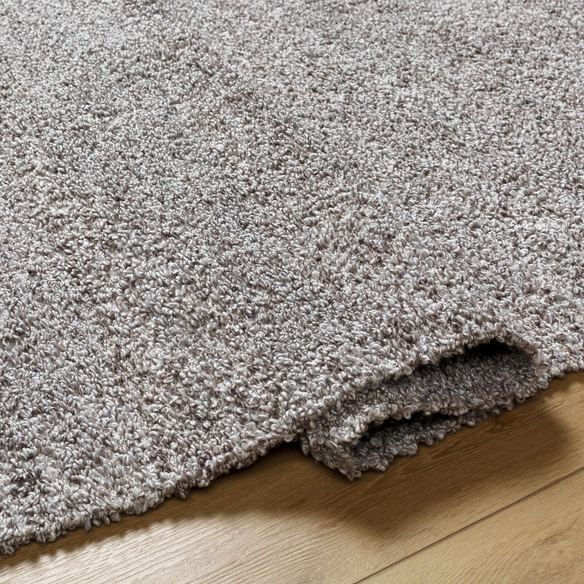 Kamil Gray Solid Area Rug by Boutique Rugs, soft gray shag pile stacked on wood floor on Tampa Home & Garden Store
