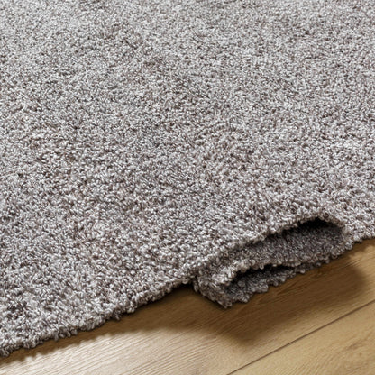Kamil Gray Solid Area Rug by Boutique Rugs, soft gray shag pile stacked on wood floor on Tampa Home & Garden Store