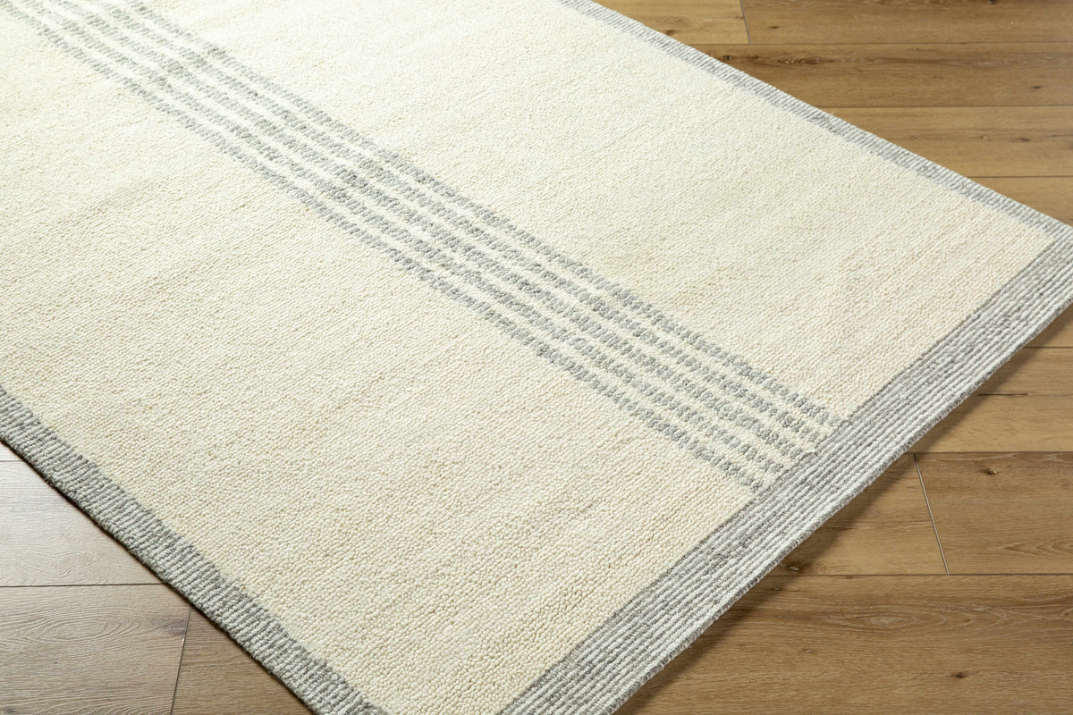 Ande Cream Area Rug by Boutique Rugs with subtle grey striped border on wood floor on Tampa Home & Garden Store