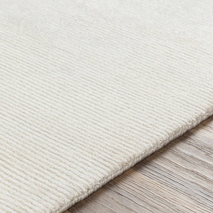 Sabinsville Carpet rug in ivory, textured pile, rolled and stacked on a wood floor on Tampa Home & Garden Store