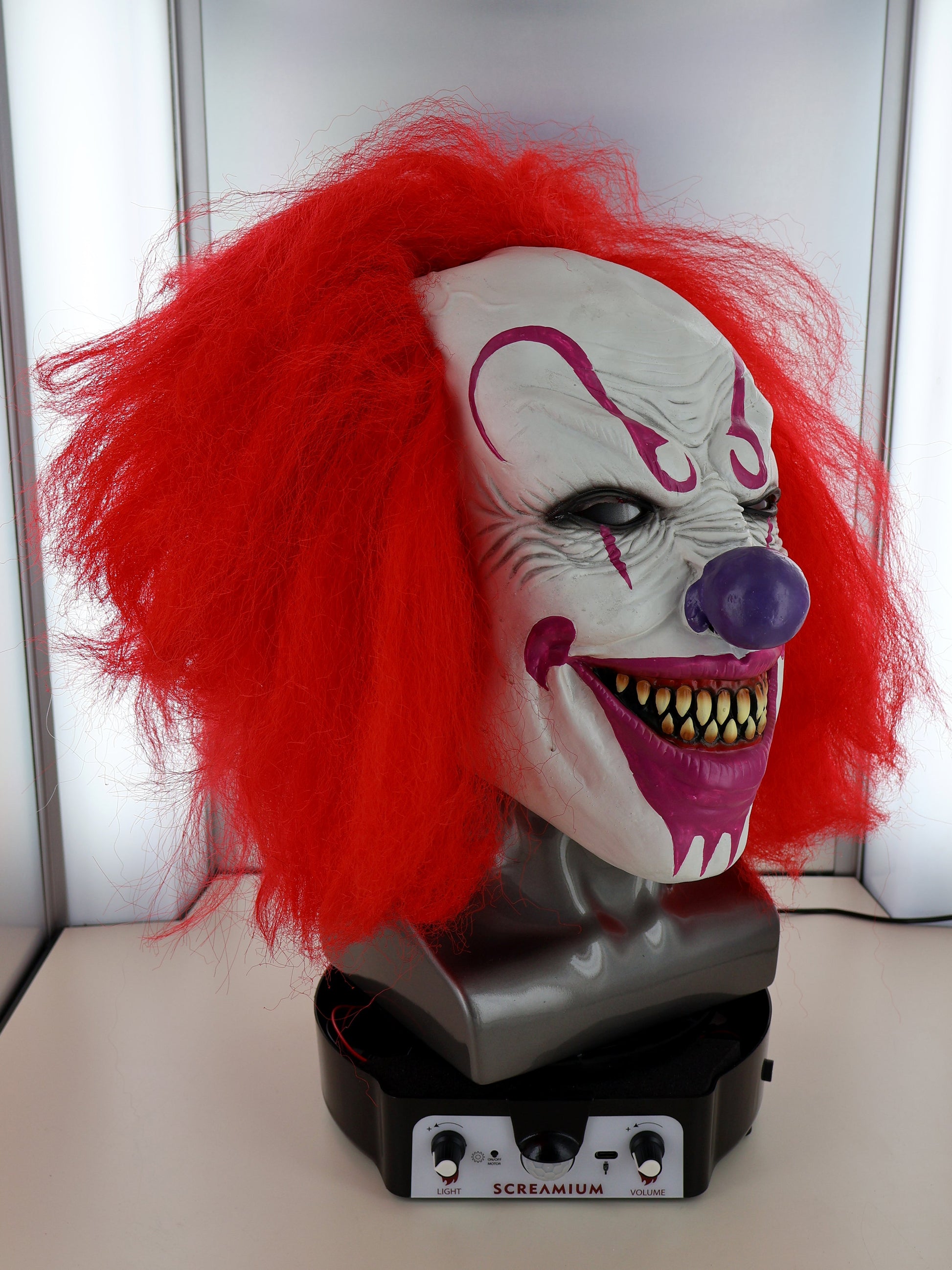 Motorized clown mask display head with red hair and snarling teeth by SCREAMIUM Halloween prop on Tampa Home & Garden Store