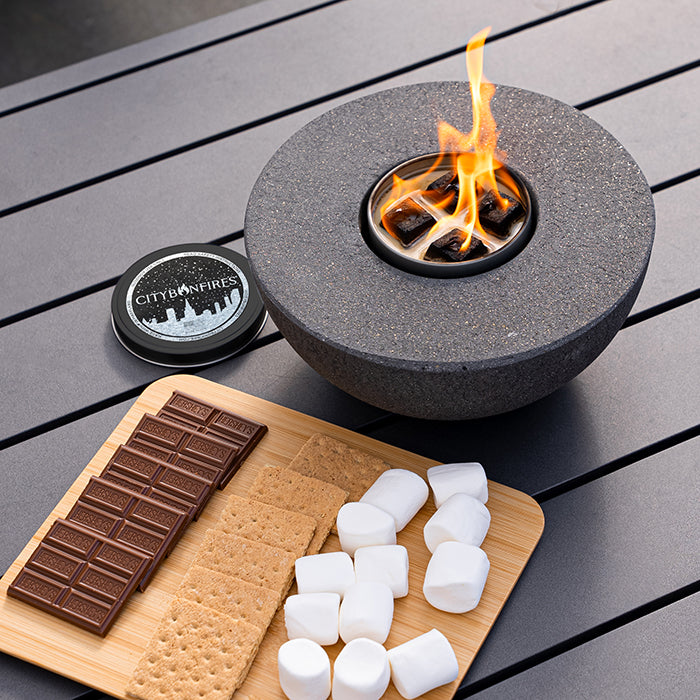 Concrete semi-round fire pit by City Bonfires with speckled gray finish and a glowing flame on Tampa Home & Garden Store