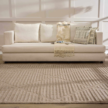 Anah Tan Outdoor Rug by Boutique Rugs; tan woven with fringe, in front of a beige sofa on Tampa Home & Garden Store