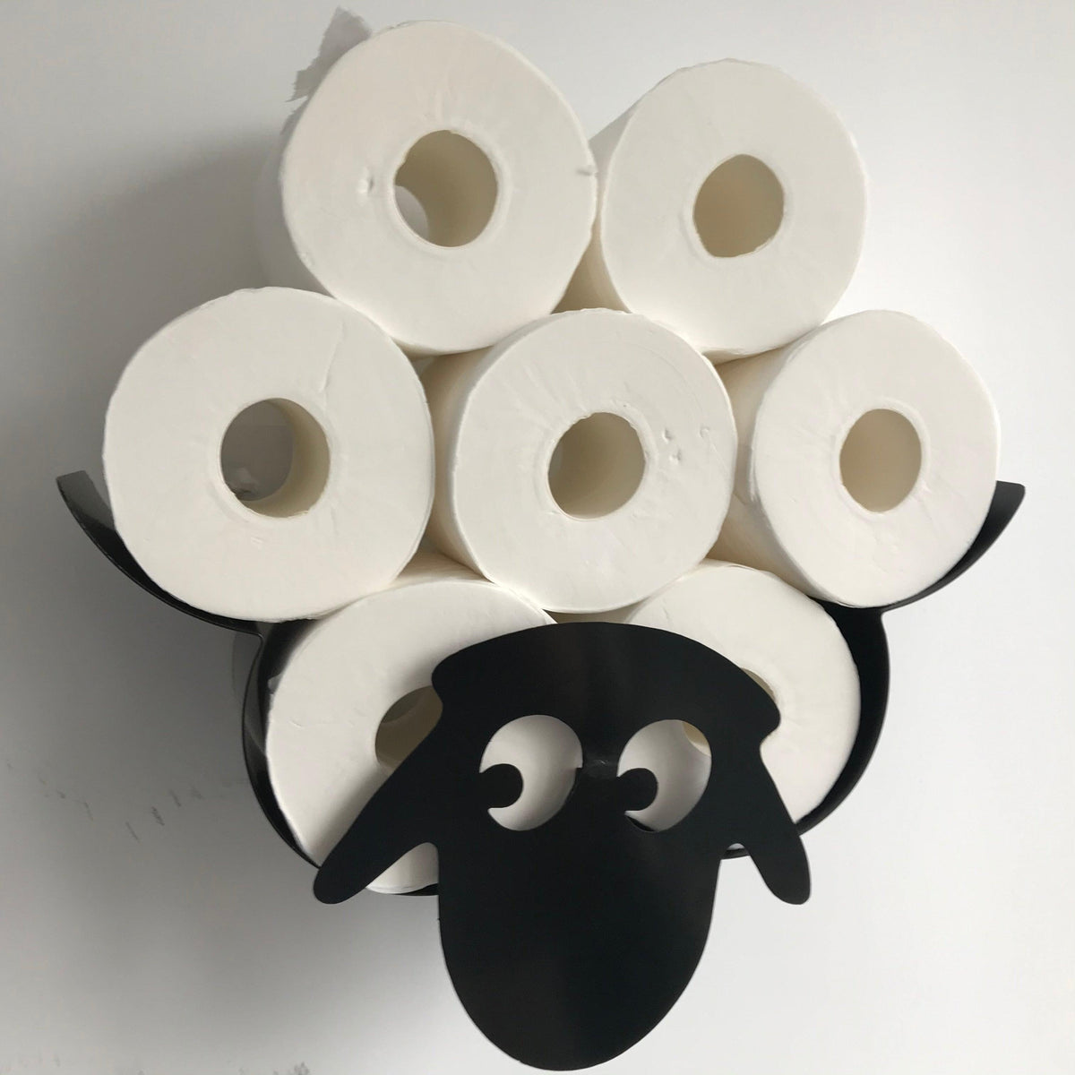 Sheep-themed toilet paper holder with nine white rolls stacked on a black rack on Tampa Home & Garden Store