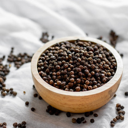 Black Pepper Plant brown peppercorns in a light wooden scoop on gray linen background on Tampa Home & Garden Store