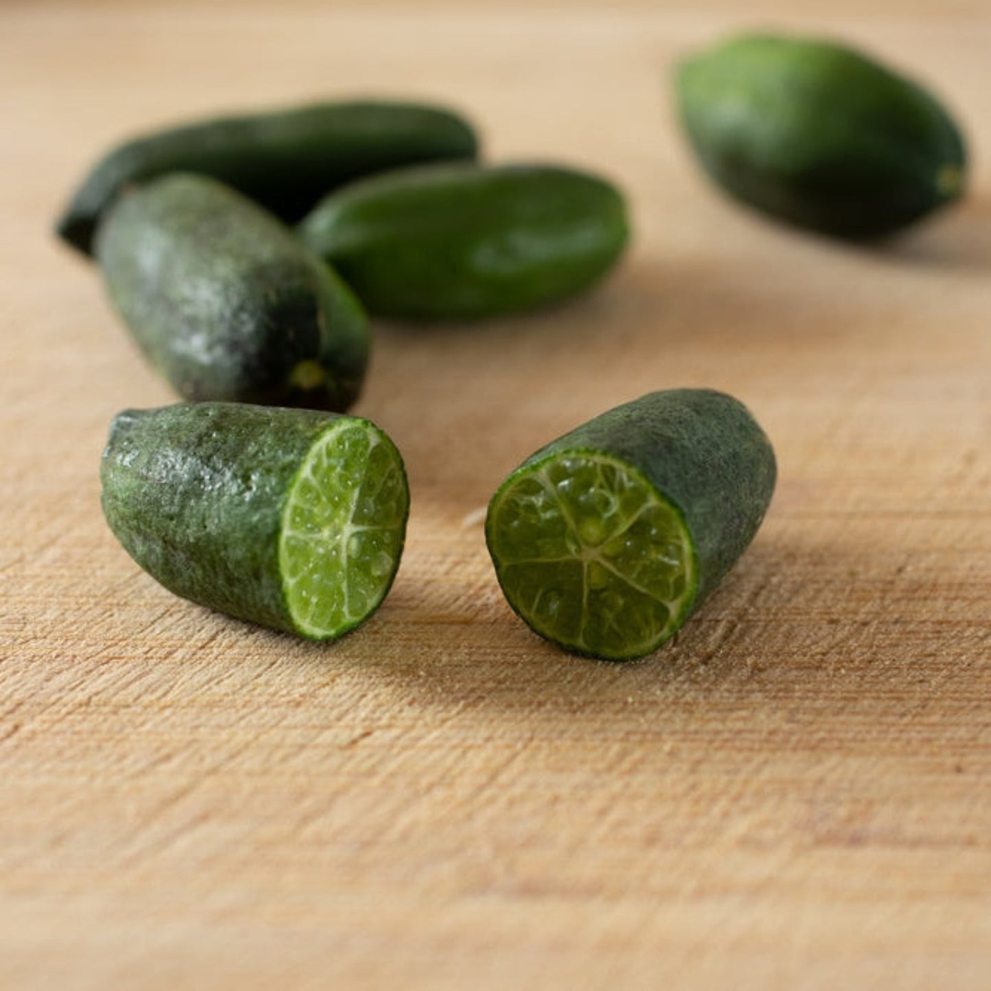 Australian finger lime tree fruit; green limes with segmented interior on wooden board on Tampa Home & Garden Store