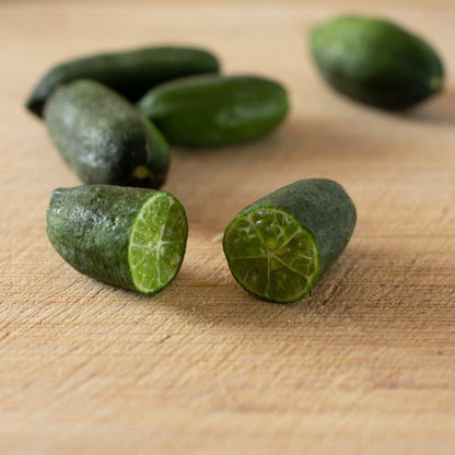 Australian finger lime tree fruit; green limes with segmented interior on wooden board on Tampa Home & Garden Store