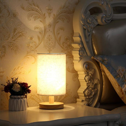 Stevvex table lamp with solid wood base and beige fabric shade on a nightstand beside a bed on Tampa Home & Garden Store