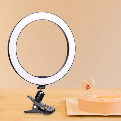 Black LED ring light with clamp mount on a tabletop beside a cake on Tampa Home & Garden Store
