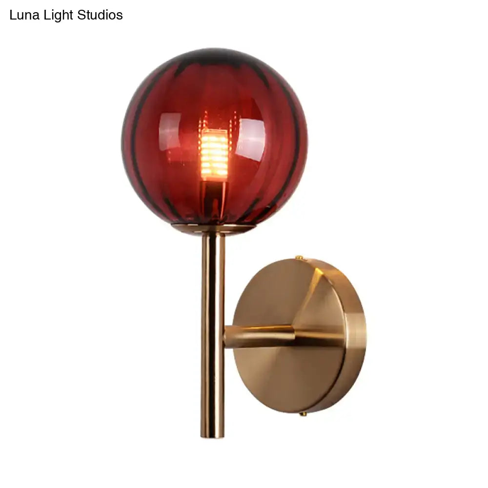 Amber red glass globe wall sconce with brass mount on wall on Tampa Home & Garden Store