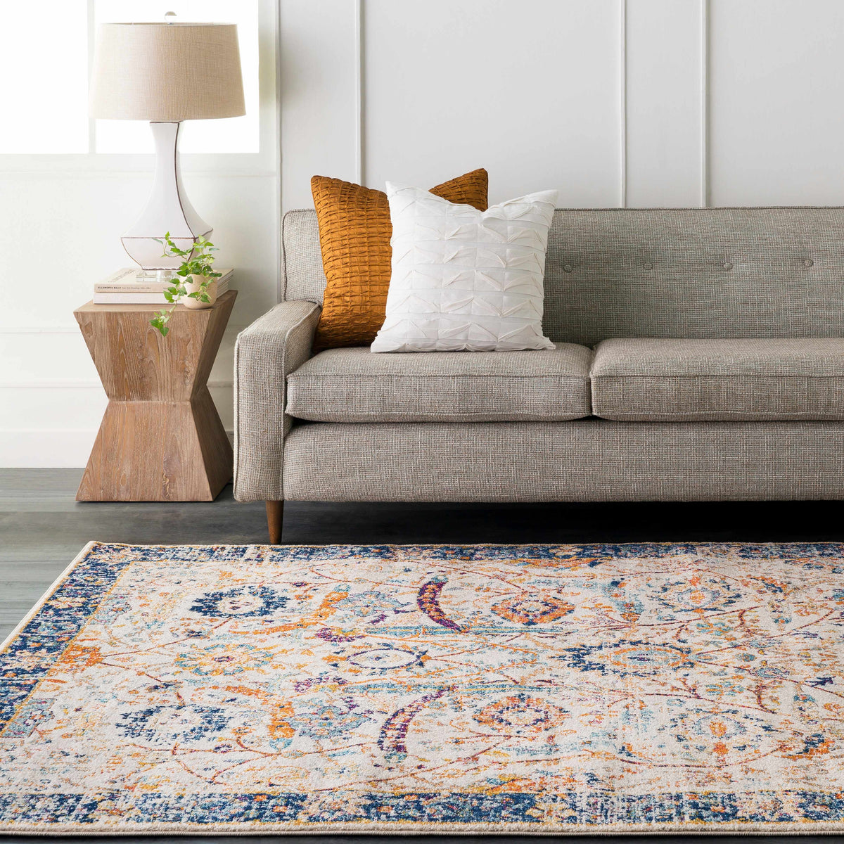 Smyrna Area Rug by Boutique Rugs with blue, orange, and white pattern beside a gray sofa on Tampa Home & Garden Store