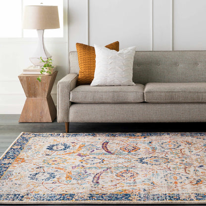 Smyrna Area Rug by Boutique Rugs with blue, orange, and white pattern beside a gray sofa on Tampa Home & Garden Store