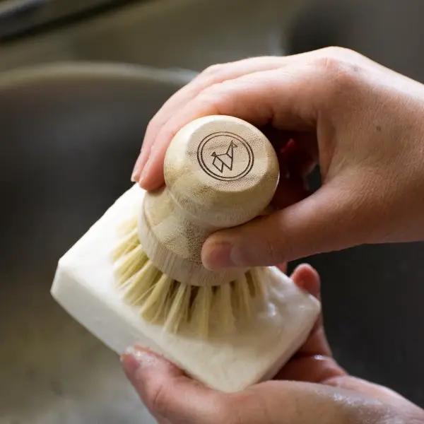 Green Llama solid coconut soap bar held beside a wooden-handled scrub brush on Tampa Home & Garden Store