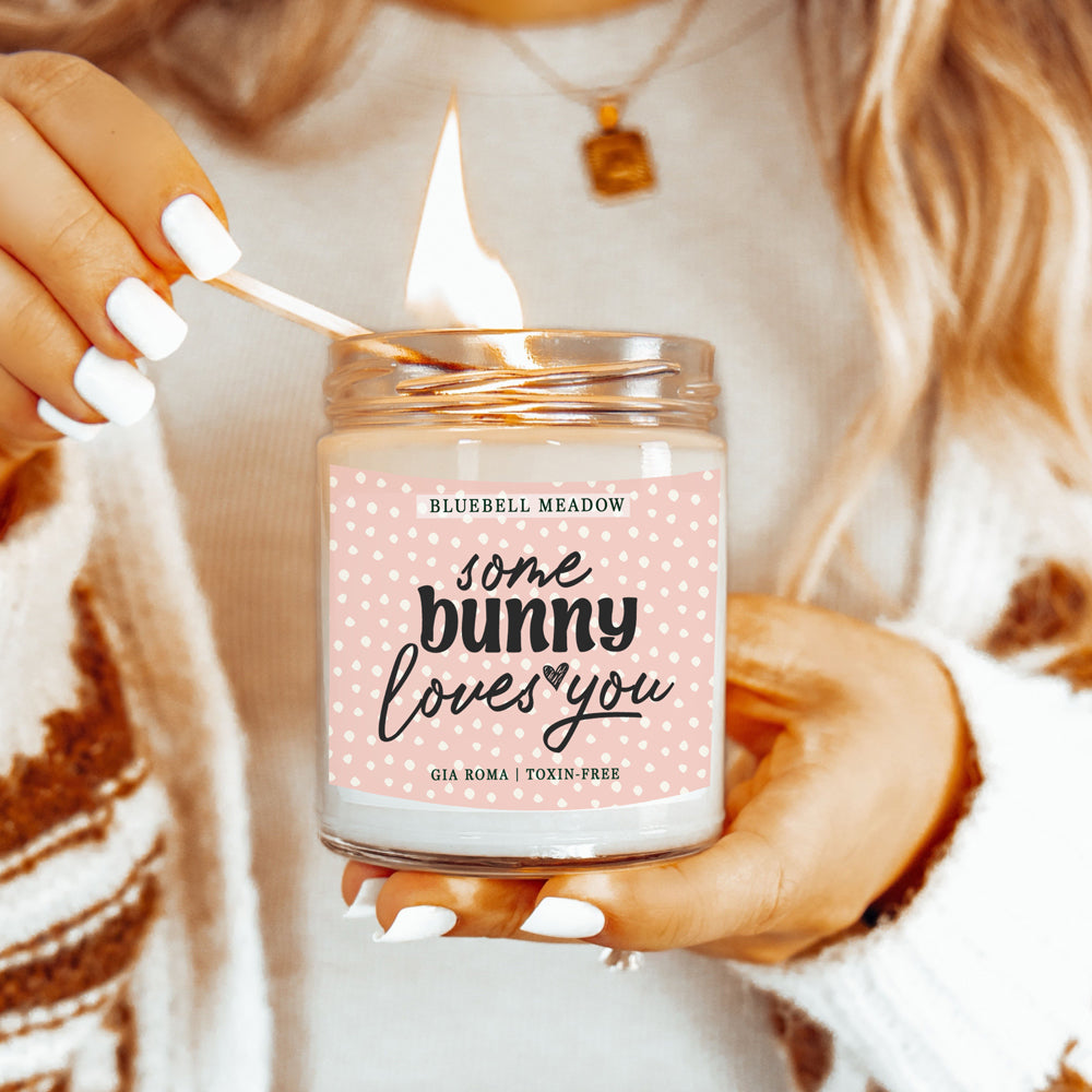 Bluebell Meadow Candle by Gia Roma in a glass jar with pink dotted label, lit with a match on Tampa Home & Garden Store