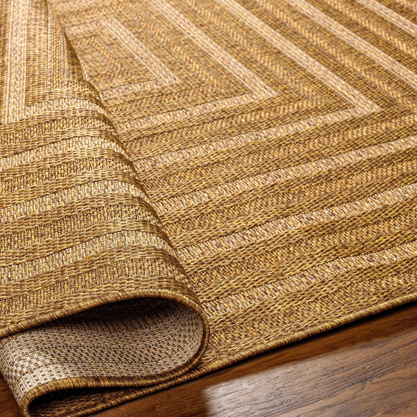 Dyami Flatweave Faux Jute Outdoor Rug in natural brown tones, 3 rolled layers on display on Tampa Home & Garden Store