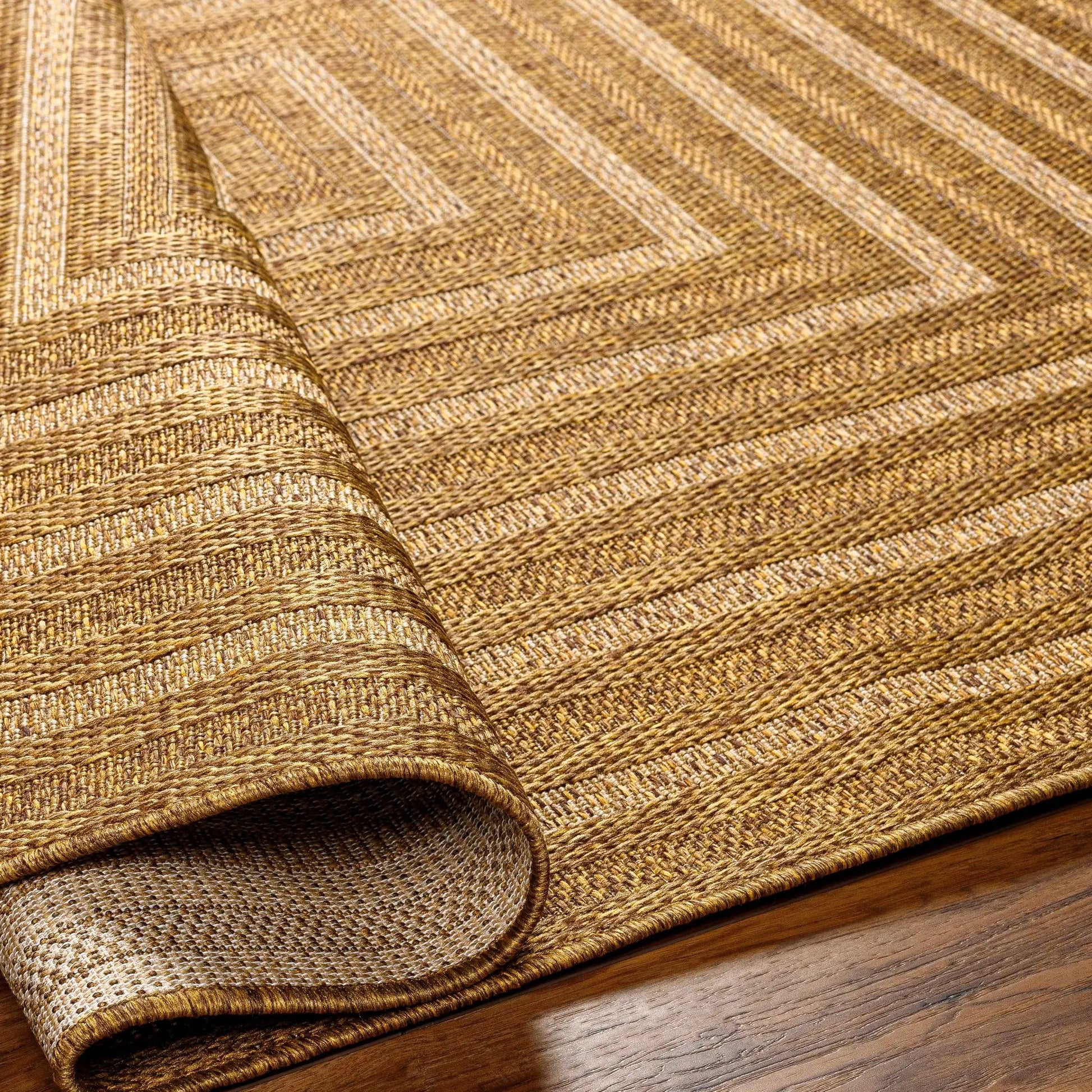 Dyami Flatweave Faux Jute Outdoor Rug in natural brown tones, 3 rolled layers on display on Tampa Home & Garden Store