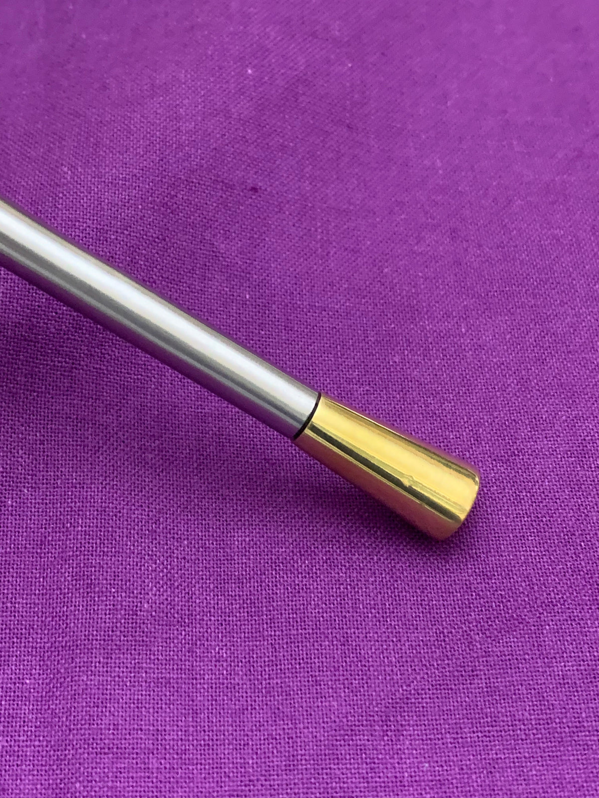 Vibhsa flatware handle with silver body and gold-tone end cap on purple fabric background on Tampa Home & Garden Store
