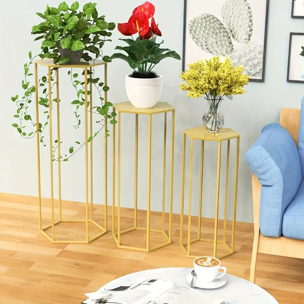 Gold hexagonal vase stand set with three tall pedestals holding green plants and a yellow bouquet on Tampa Home & Garden Store
