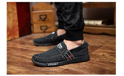 Stevvex men's black canvas slip-on shoes with white stitching and rubber sole on wooden floor on Tampa Home & Garden Store