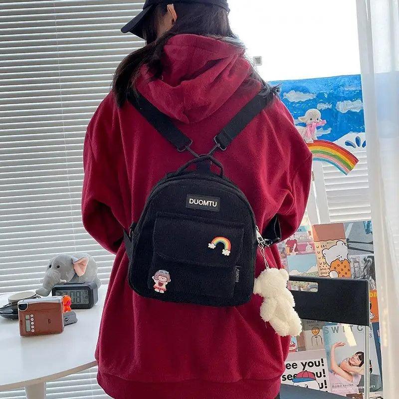 Stevvex backpack with DUOMTU; black bag with rainbow patch worn by girl in red hoodie on Tampa Home & Garden Store