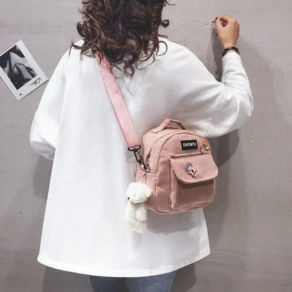 Small pink Stevvex backpack with front pocket, cartoon patches, and white plush keychain on Tampa Home & Garden Store