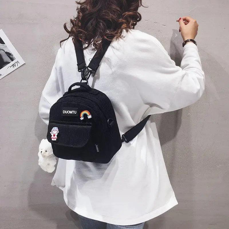 Small black backpack with front zip pocket patches, rainbow patch and plush keychain on Tampa Home & Garden Store