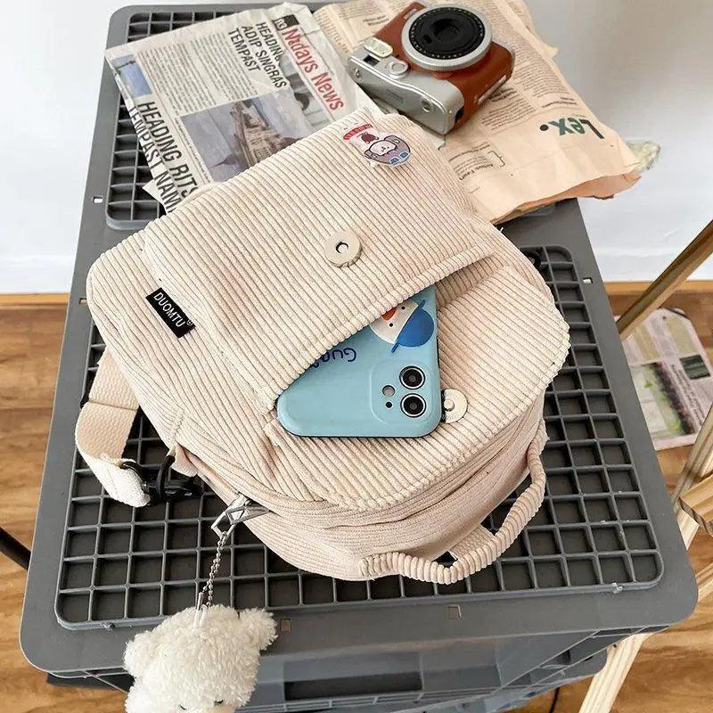 Stevvex small beige corduroy backpack with front pocket, top flap button, and fluffy pompom charm on Tampa Home & Garden Store