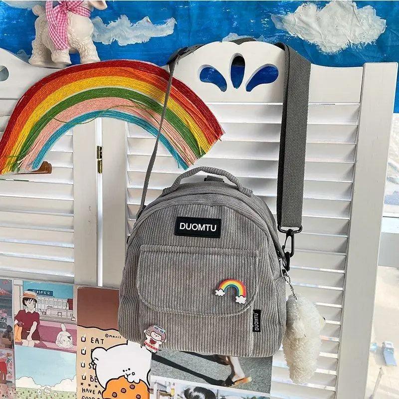 Grey corduroy backpack DUOMTU with rainbow arc patch and fluffy pom keychain on Tampa Home & Garden Store