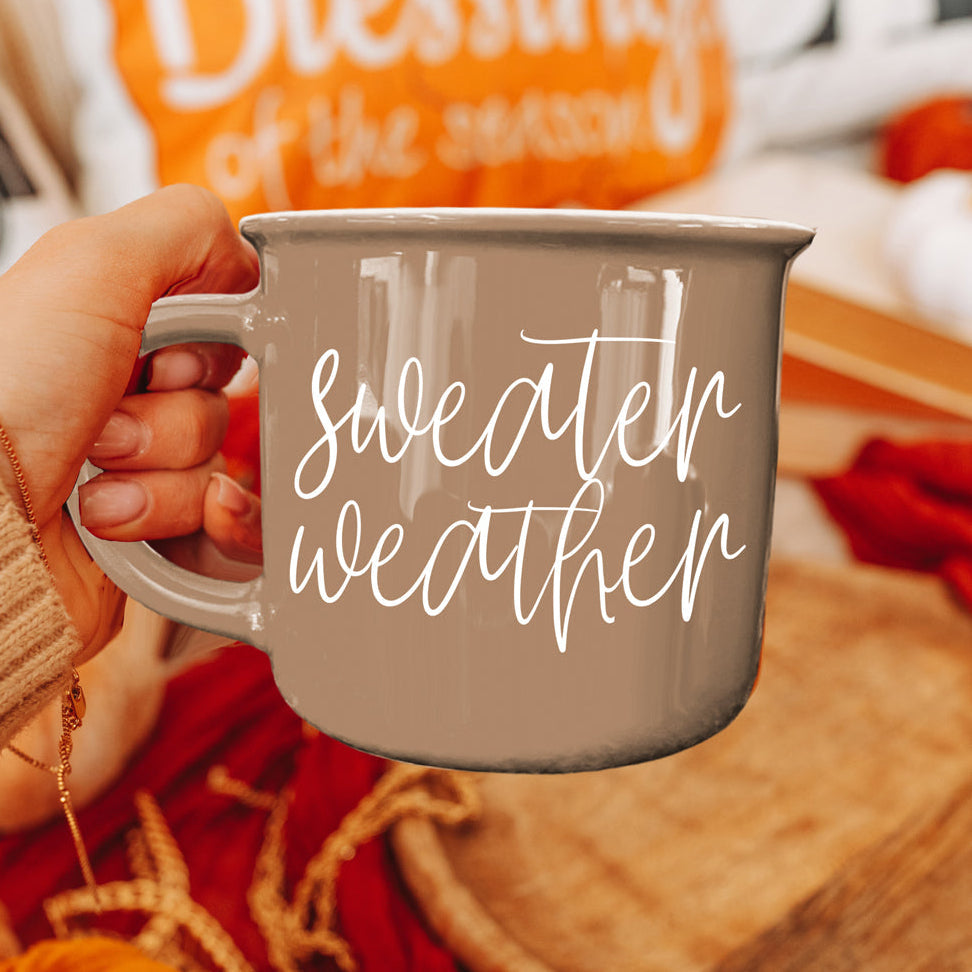 Gray ceramic coffee mug with white cursive sweater weather design, held by hand on Tampa Home & Garden Store