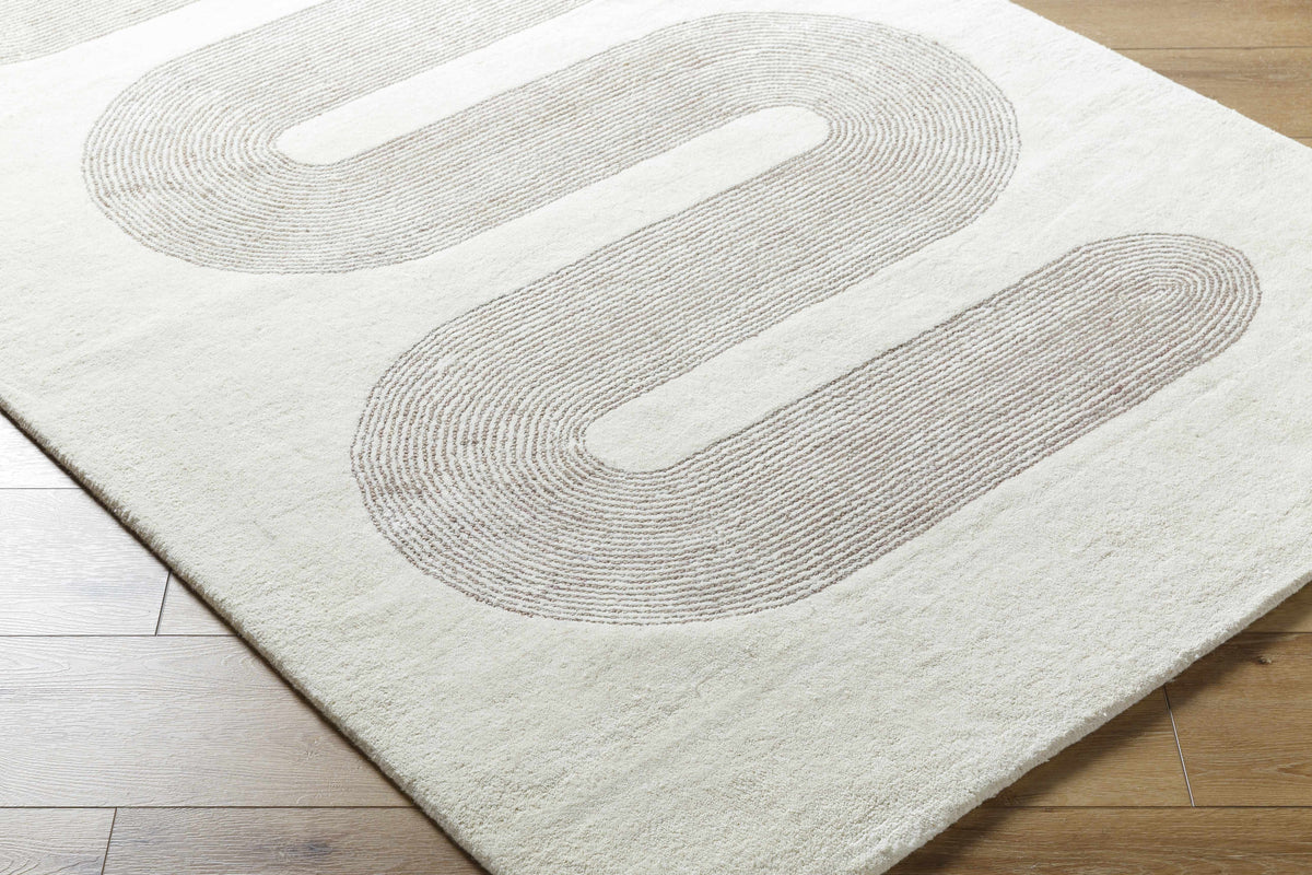 Saura area rug with cream background and taupe curved line pattern on light wood floor on Tampa Home & Garden Store