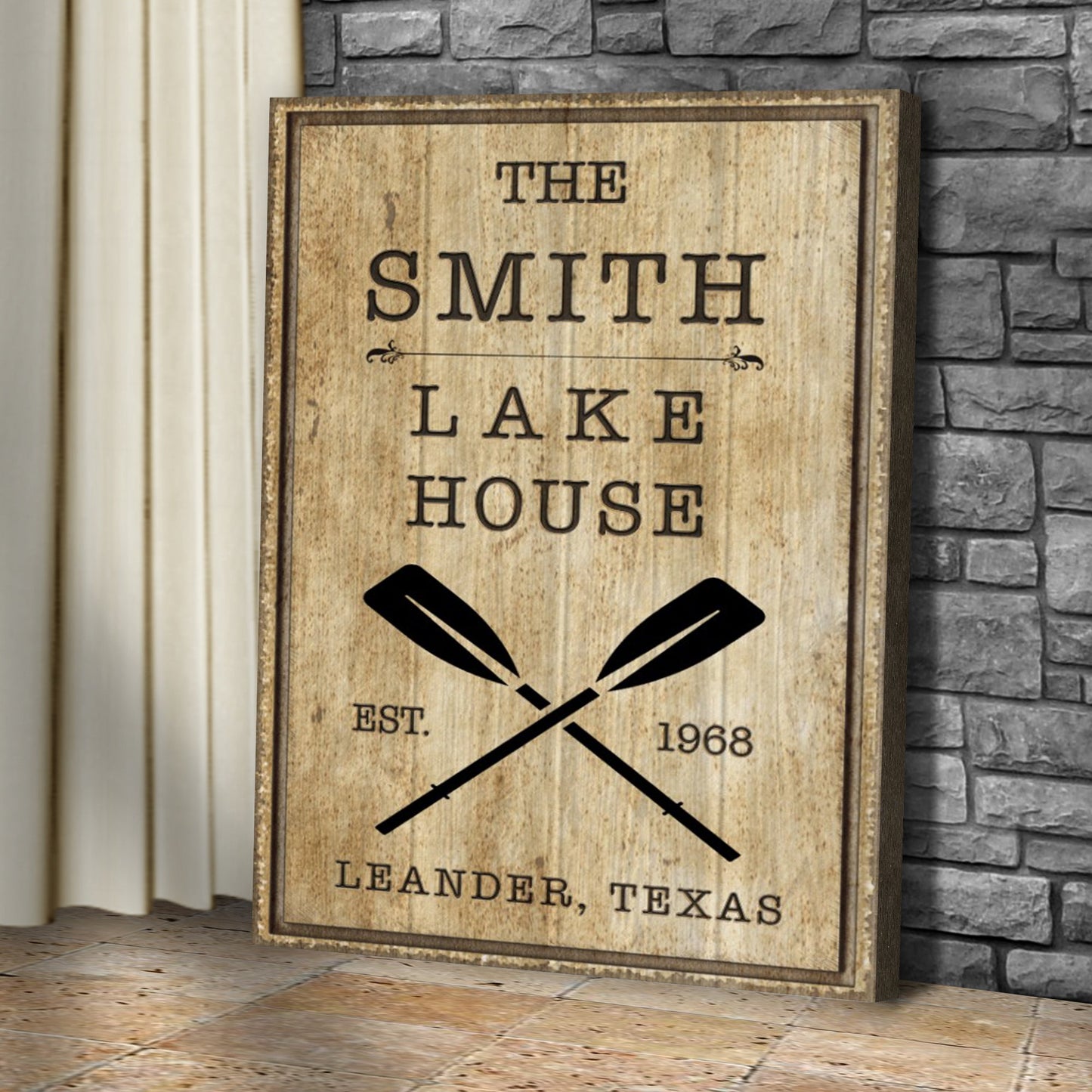 Family Lake House Rustic Sign II canvas artwork by Tailored Canvases leaning against a stone wall on Tampa Home & Garden Store