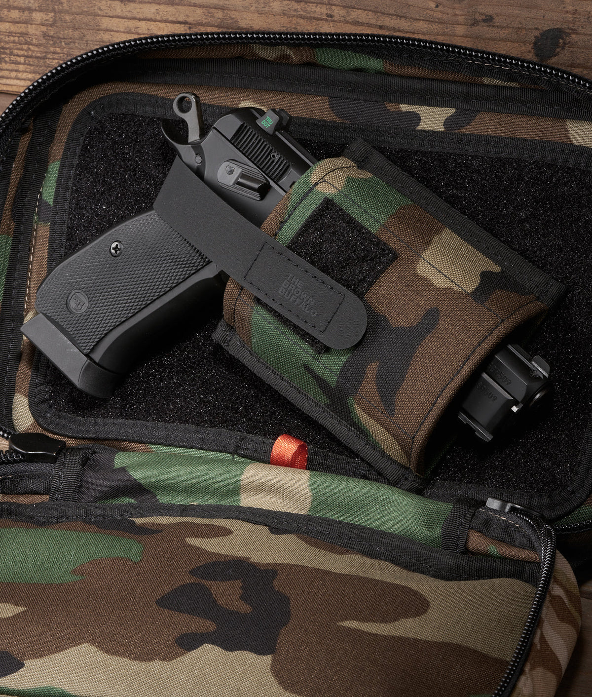 Muzzle Mask accessory: black handgun in camo bag with The Brown Buffalo branding strap on Tampa Home & Garden Store