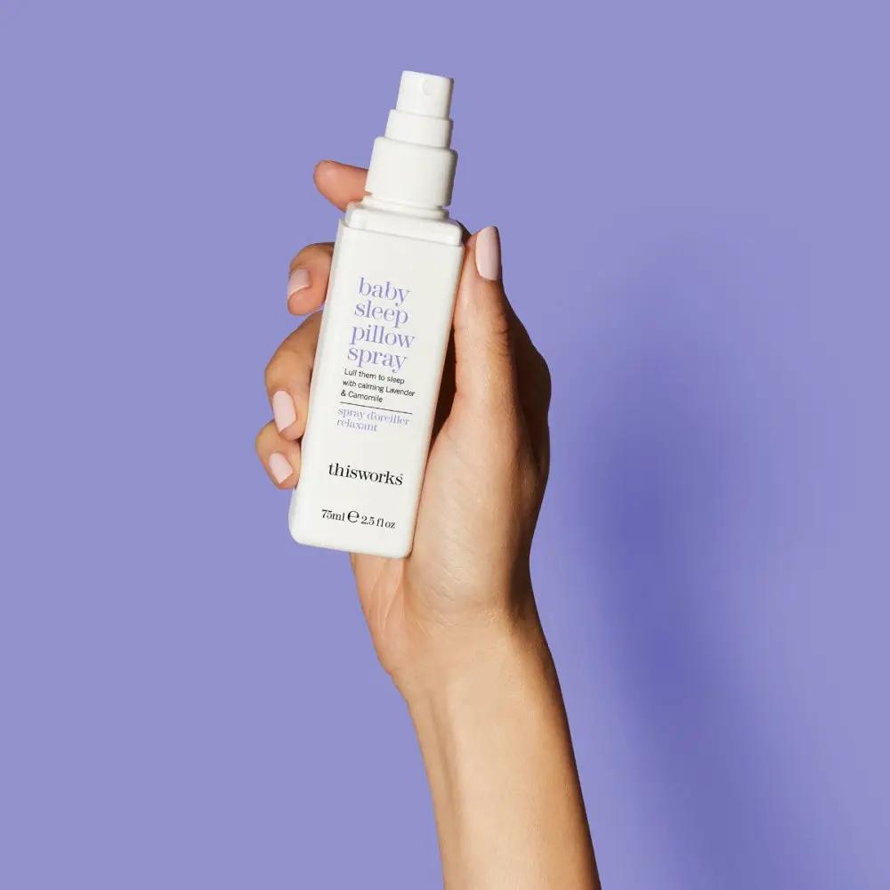 This Works Baby Sleep Pillow Spray 2.5oz white spray bottle with lavender text held in hand on Tampa Home & Garden Store