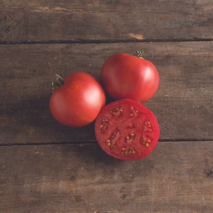 Moskvich tomato fruits: three ripe red tomatoes, one cut in half to show interior seeds on Tampa Home & Garden Store