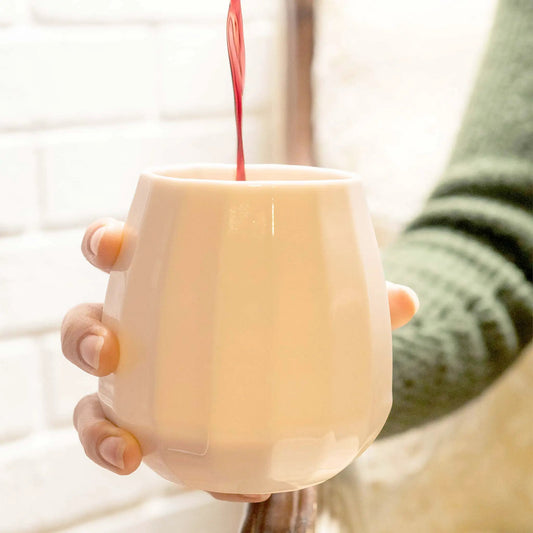 Translucent porcelain wine glass held by hands as red wine streams into it in a bright kitchen on Tampa Home & Garden Store
