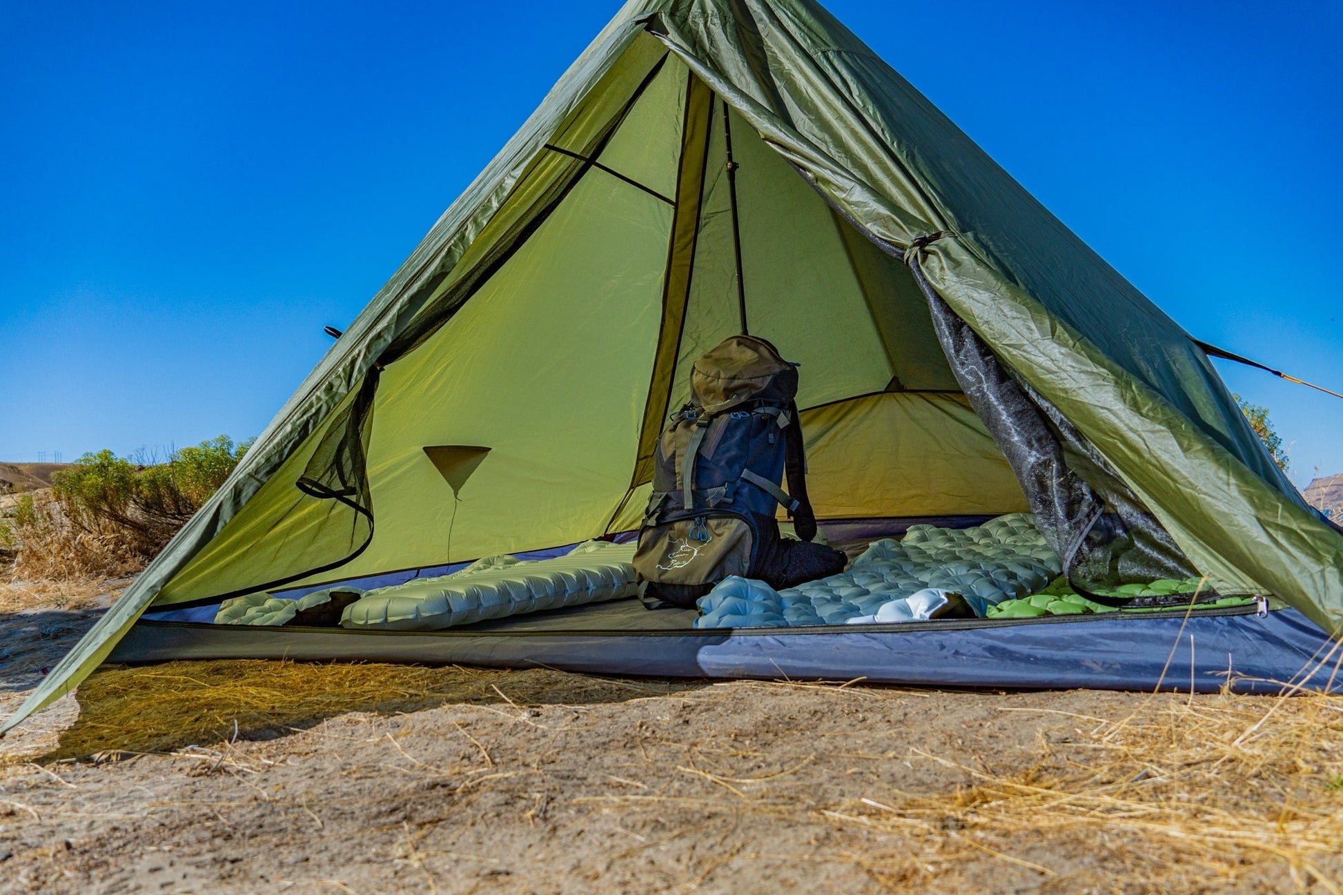 Trekker Tent 4 green pyramid tent with backpack and sleeping pads inside on Tampa Home & Garden Store