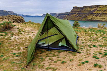 Trekker Tent 2V, green 2-person backpacking tent set up on sandy lakeshore with canyon cliffs on Tampa Home & Garden Store