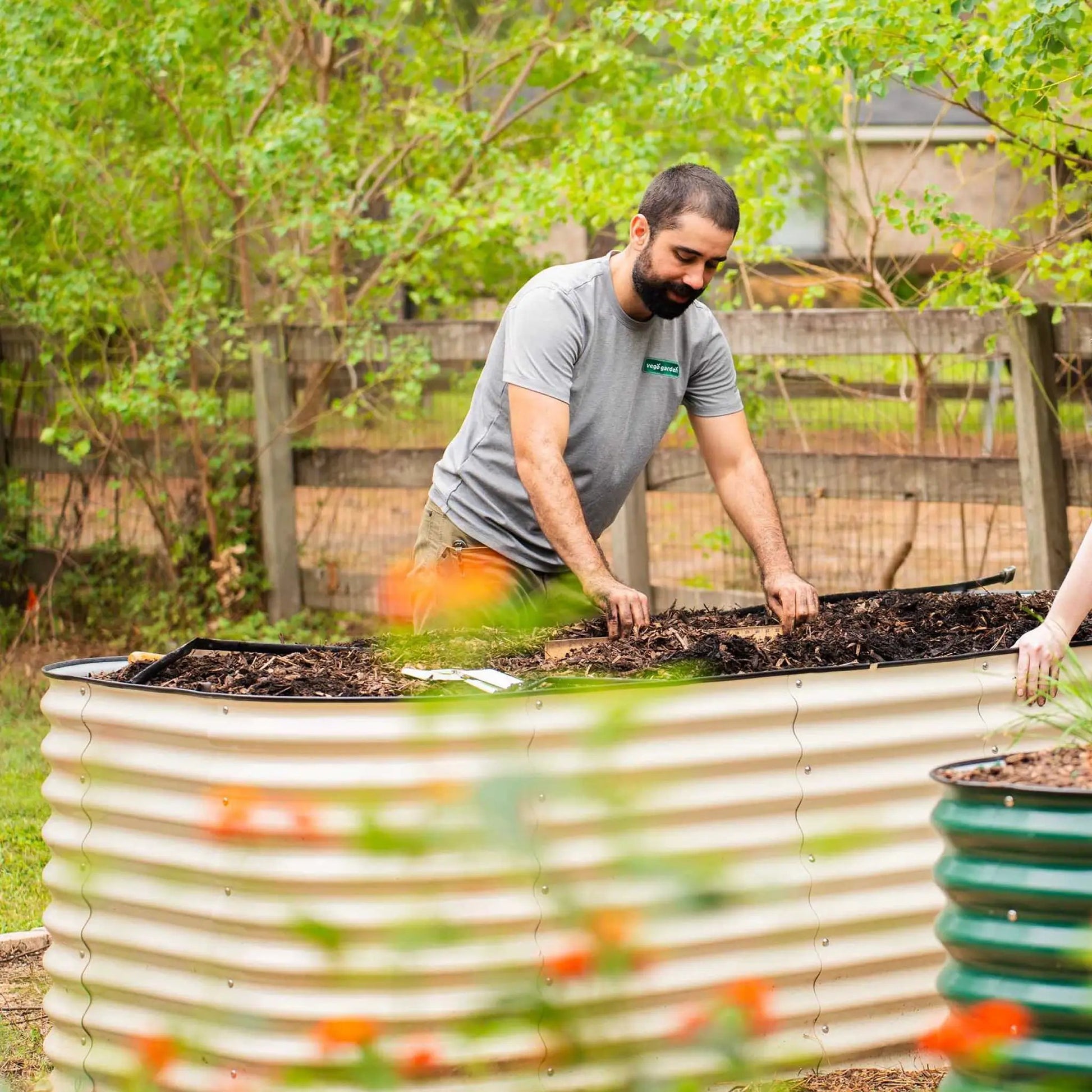 32-inch tall modular raised garden bed in a round metal planter, gardener at work on Tampa Home & Garden Store