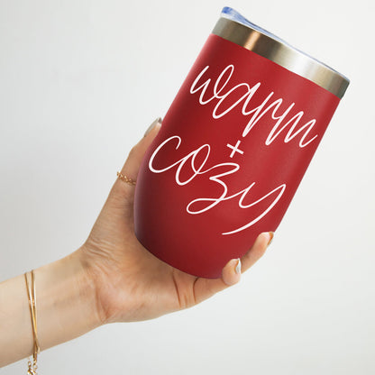 Tumbler 17oz red with white Warm + Cozy script and stainless steel rim held in a hand on Tampa Home & Garden Store