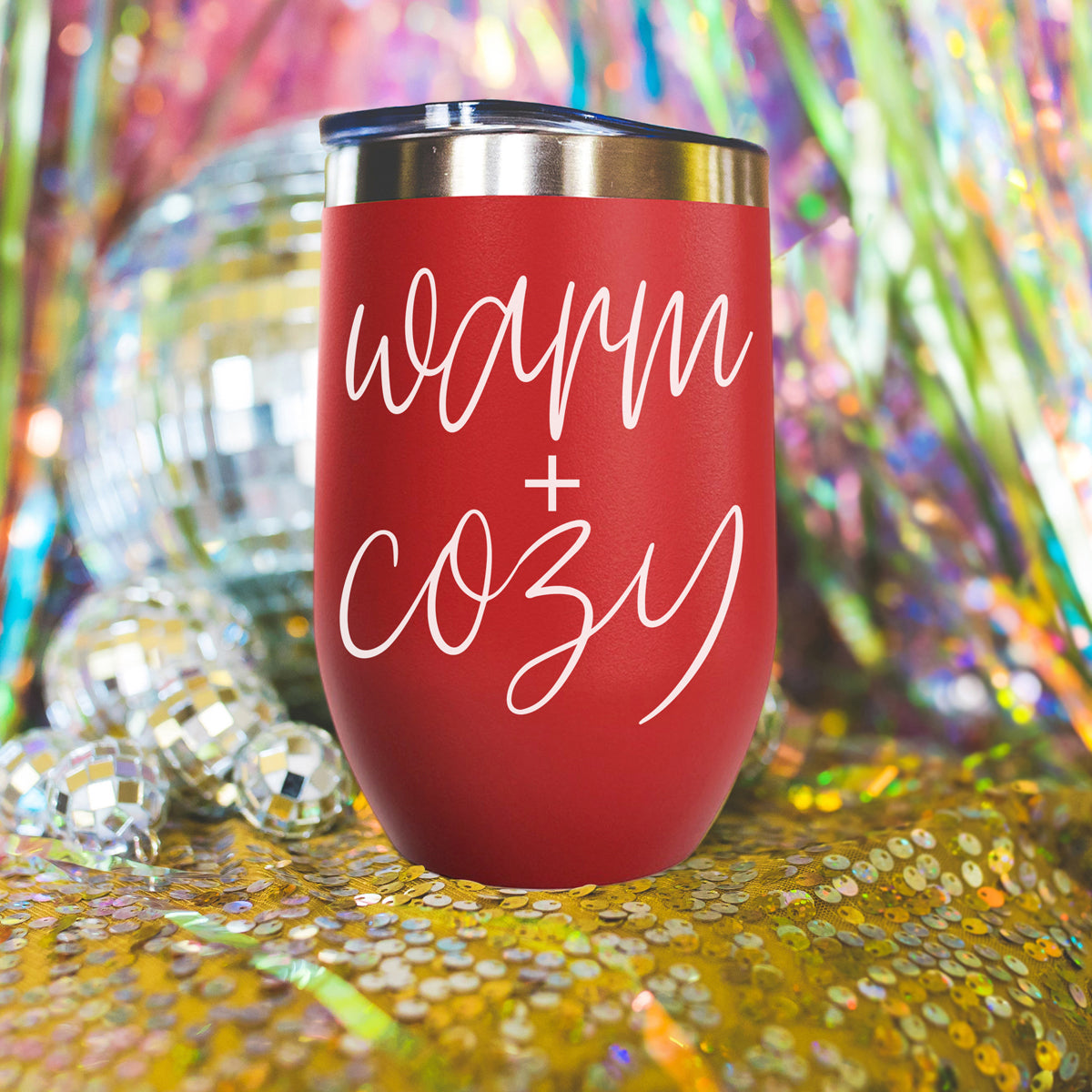 Warm + Cozy 17oz red tumbler by Gia Roma with stainless lid amid disco balls and confetti on Tampa Home & Garden Store