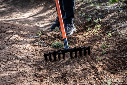 Weston rake by Backslope Tools with orange handle and black tined head in dirt on Tampa Home & Garden Store