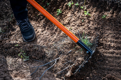 Weston rake with orange handle and black head, visible dirt and boot nearby in soil on Tampa Home & Garden Store