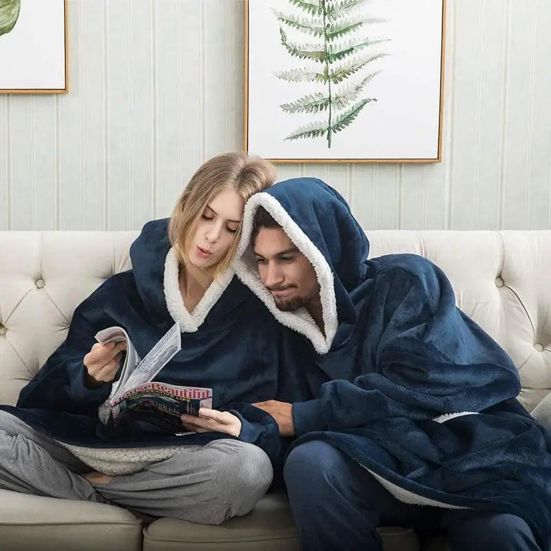 Stevvex navy blue wearable blanket hoodie with white sherpa lining worn by a couple on a sofa on Tampa Home & Garden Store