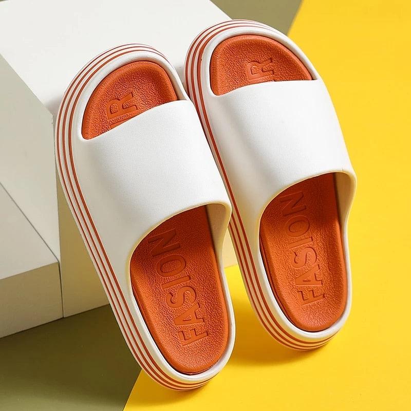 Pair of white women's EVA slippers with orange footbeds and striped thick sole open toe on Tampa Home & Garden Store
