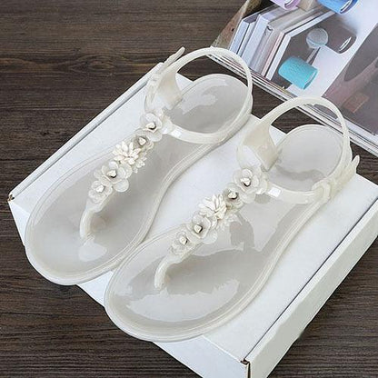 Women's jelly sandals with white floral embellishments, clear straps and T-strap design, pair on Tampa Home & Garden Store
